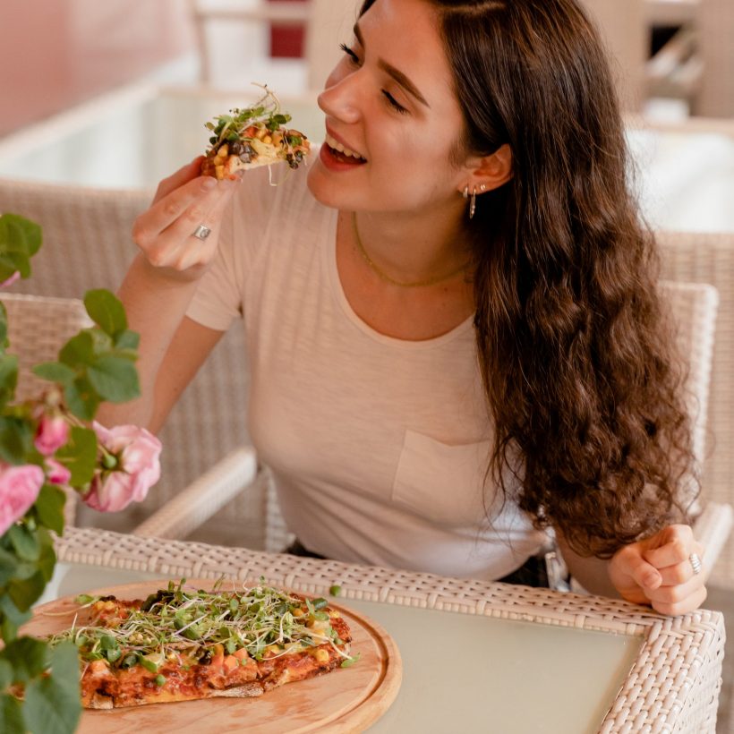 Girl with pinsa romana in cafe on summer terrace. Young woman eating pinsa and drinking wine.
